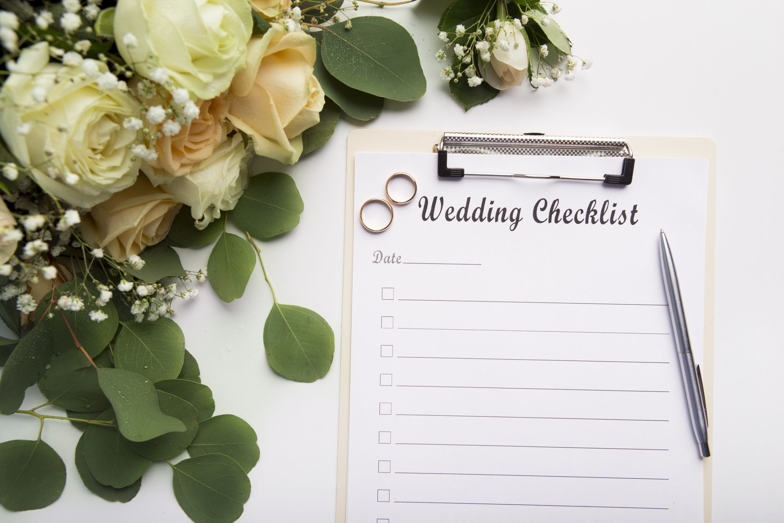 Creative wedding planning checklist with roses and rings on white background, copy space