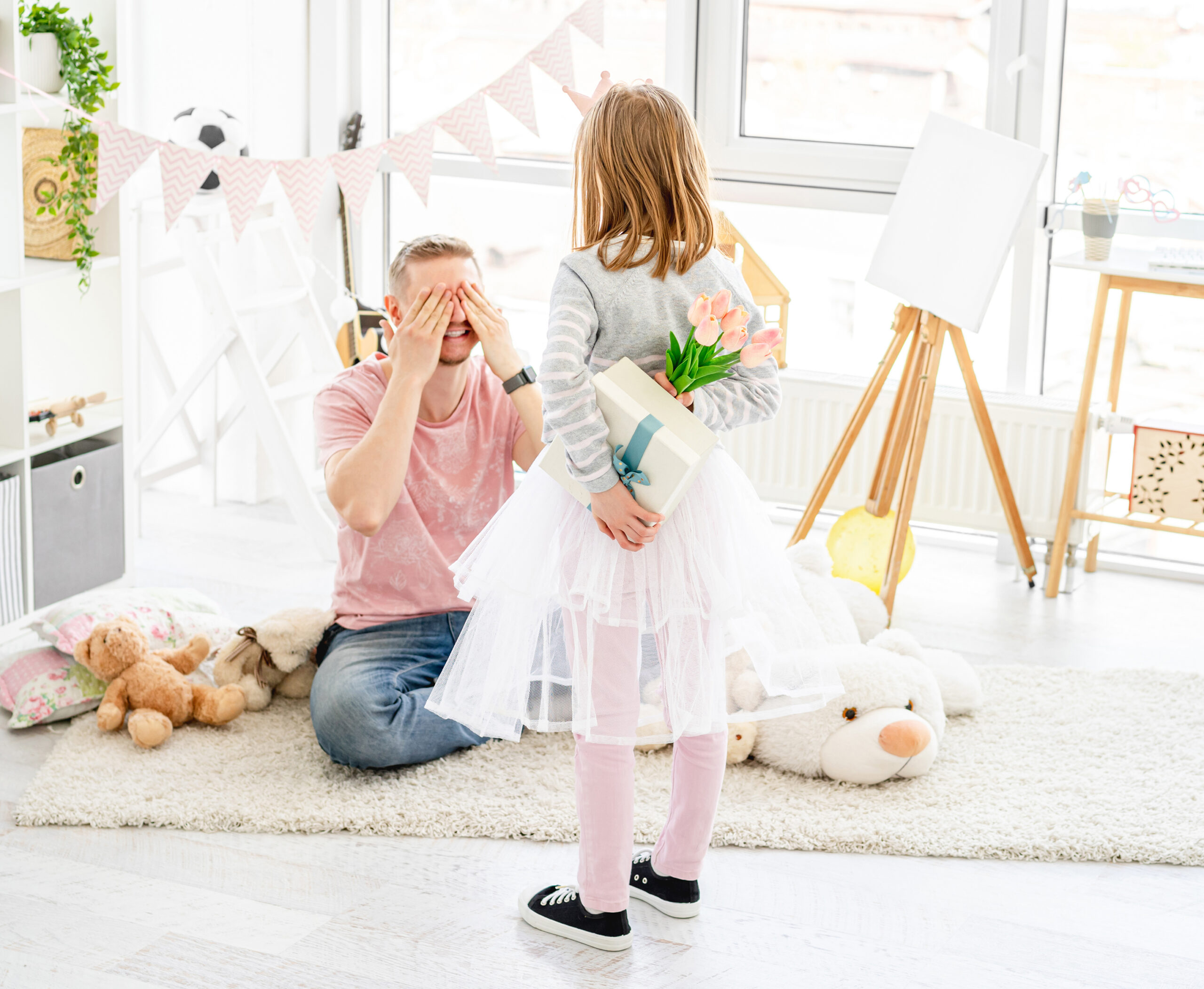 Little girl with gift for excited father in playroom
